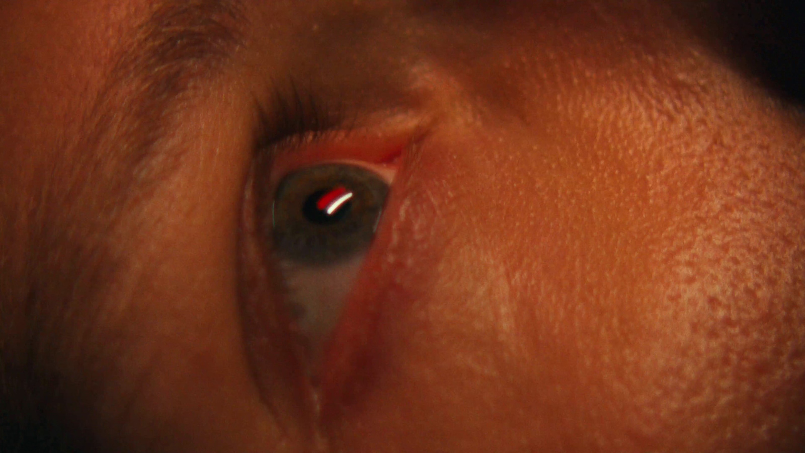 a close up of a person's eye with a red light in the center