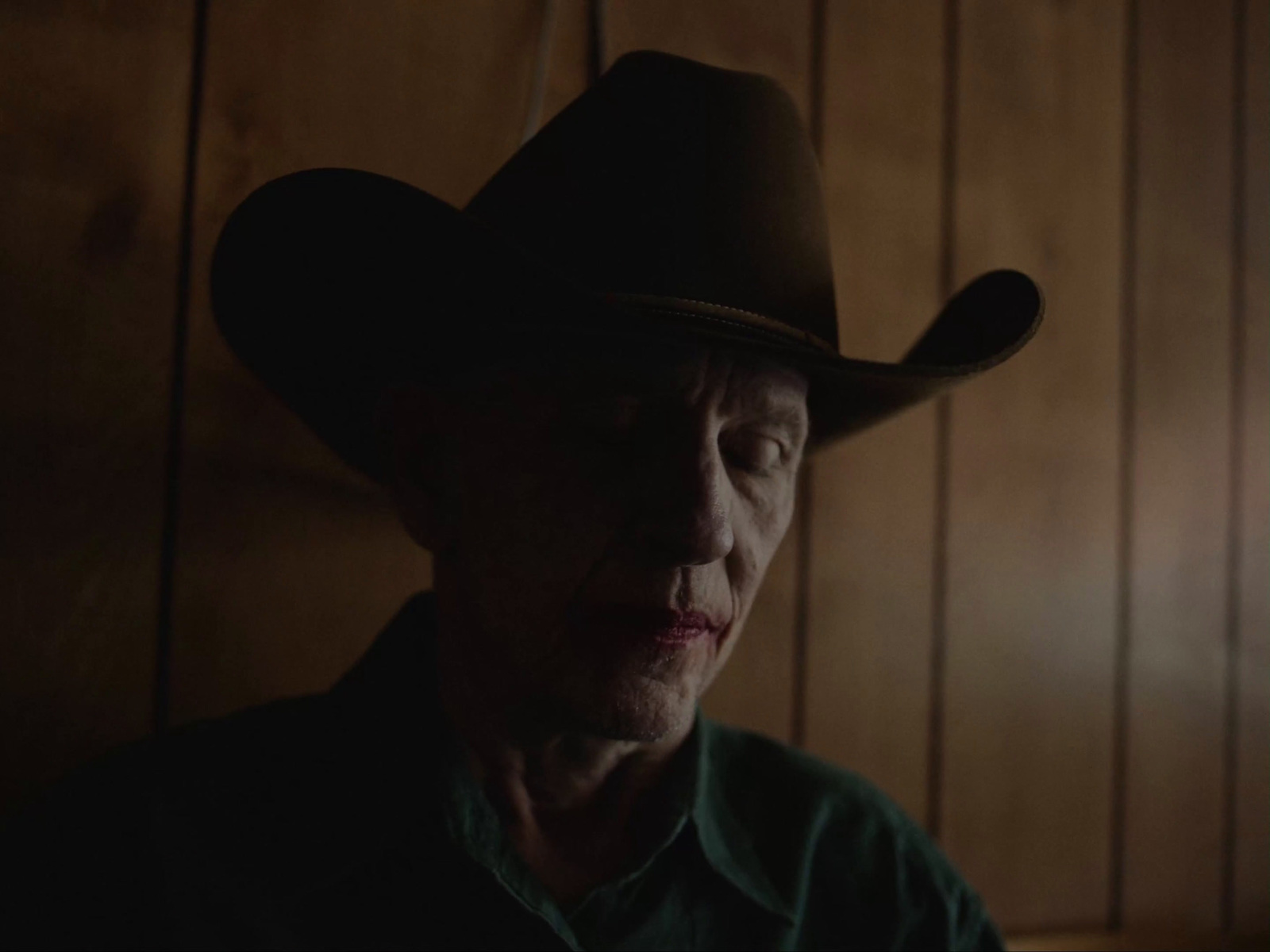 an older man wearing a cowboy hat in a dark room