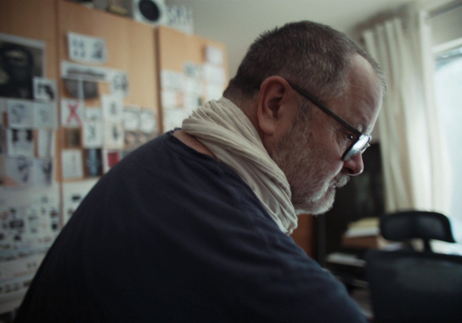 a man with a scarf around his neck looking at a computer screen