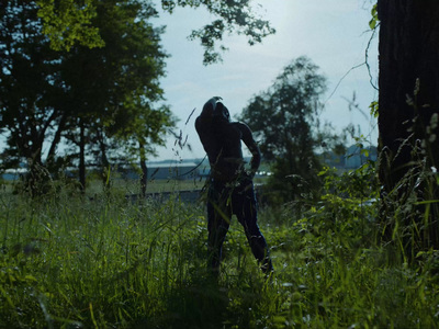 a man standing in a field next to a tree