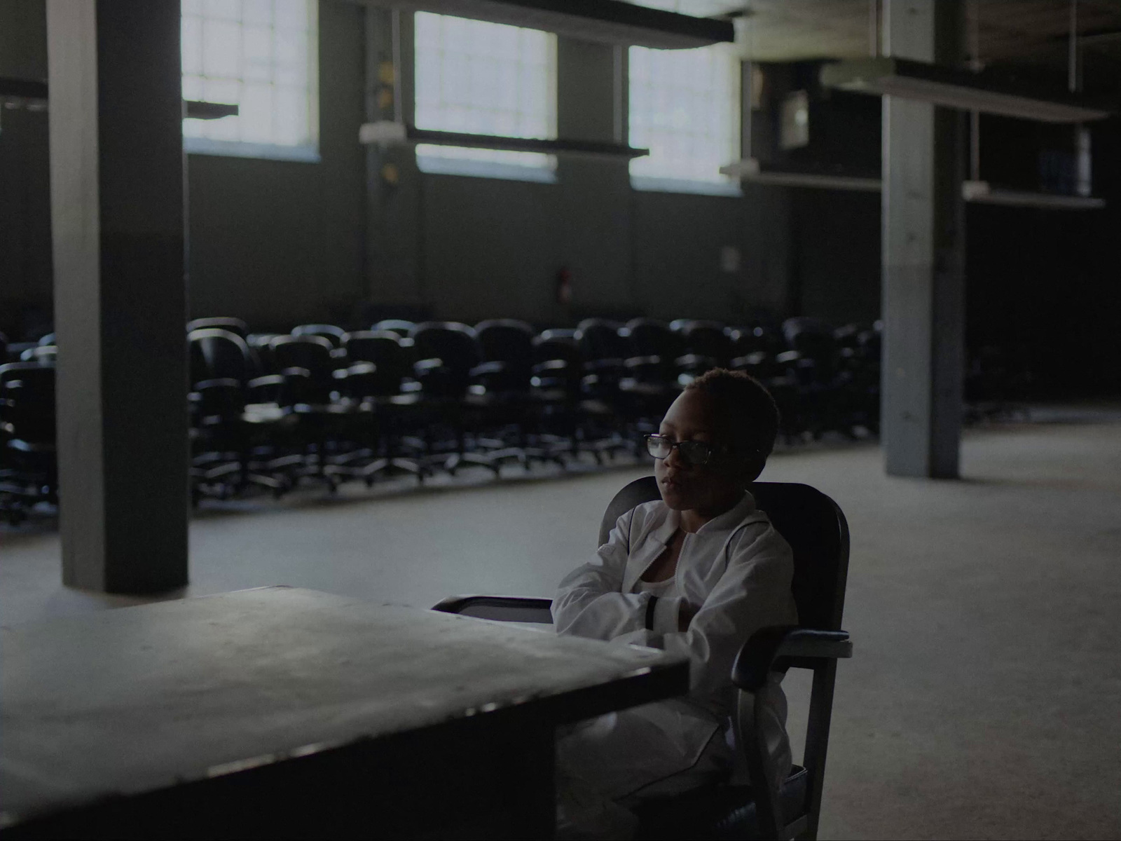 a woman sitting at a table in an empty room