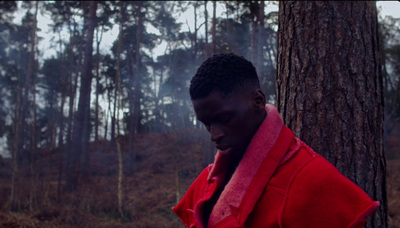 a man in a red jacket standing next to a tree