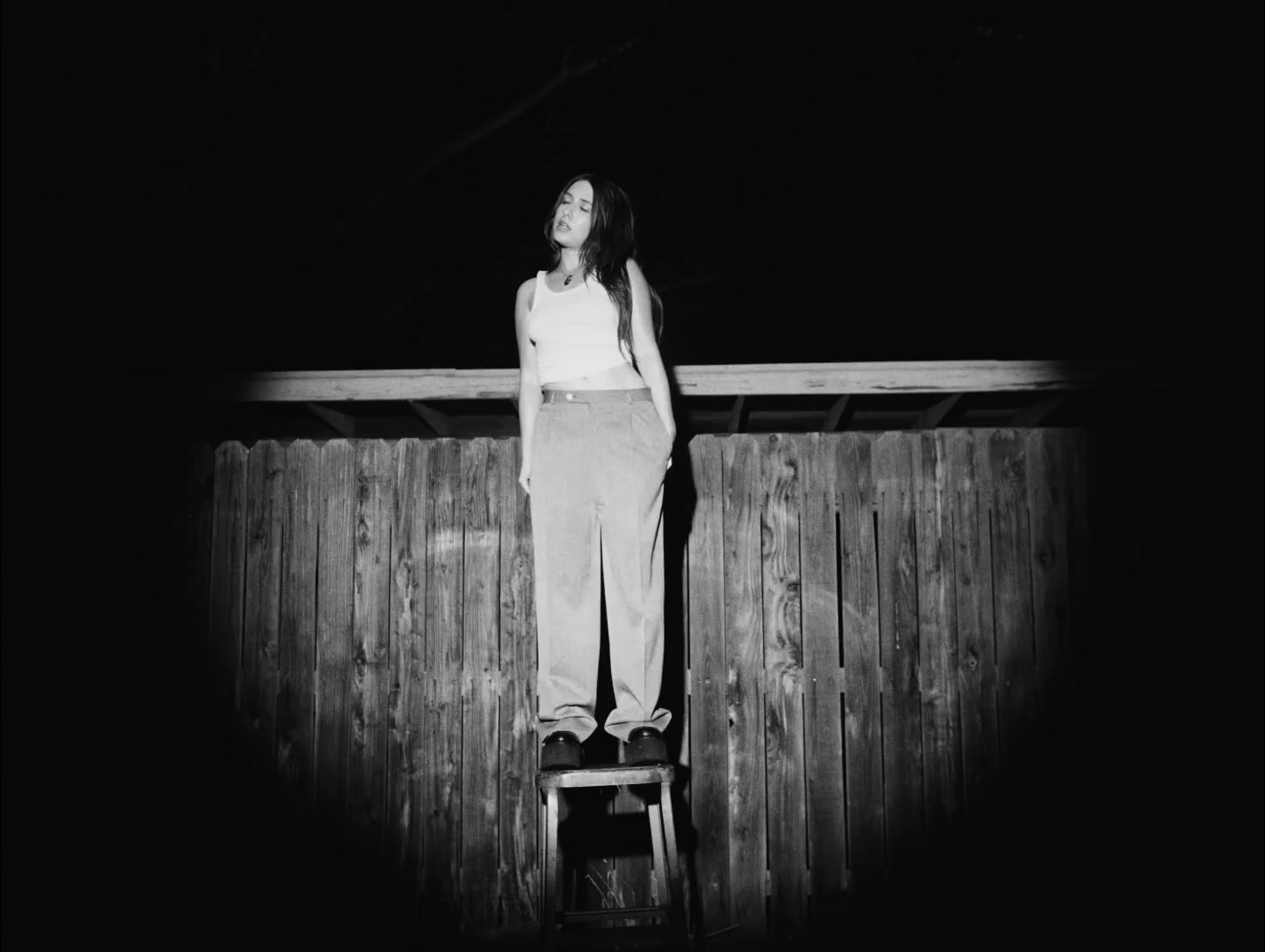 a black and white photo of a woman standing on a ladder