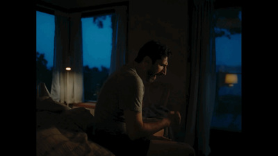 a man sitting on a bed in a dark room