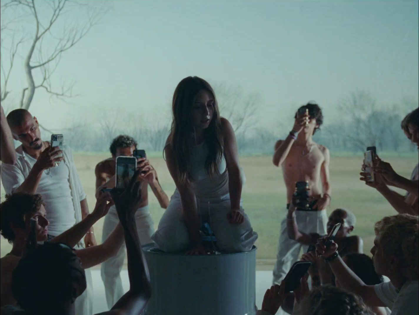 a woman sitting on top of a cake surrounded by people