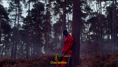 a man in a red outfit standing next to a tree