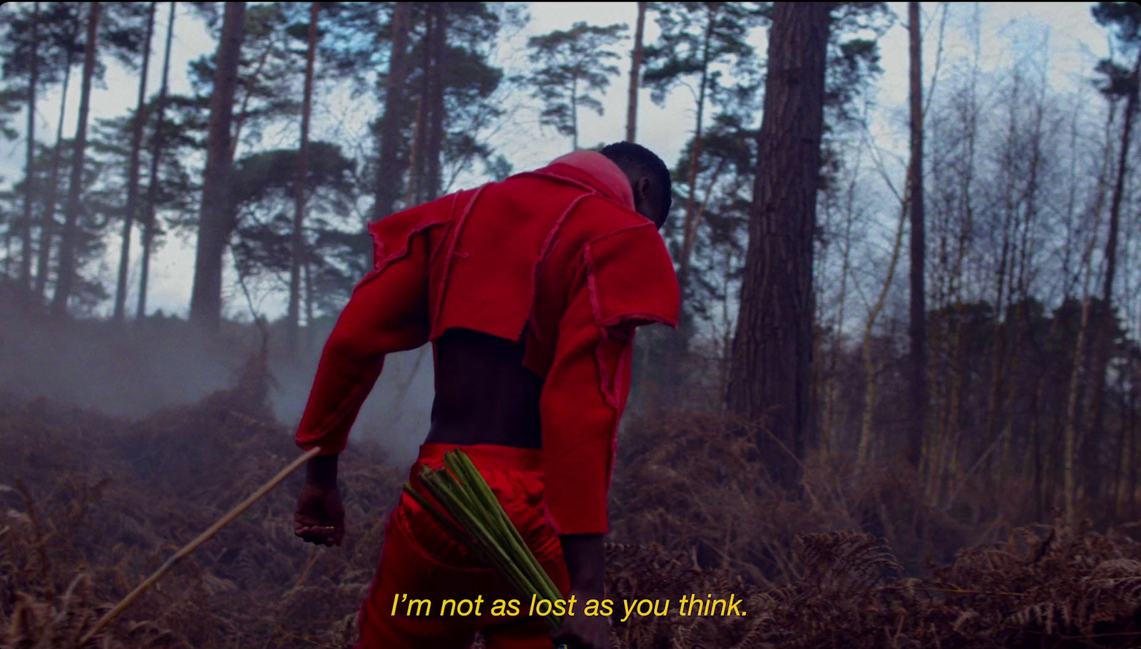 a man in a red outfit walking through a forest