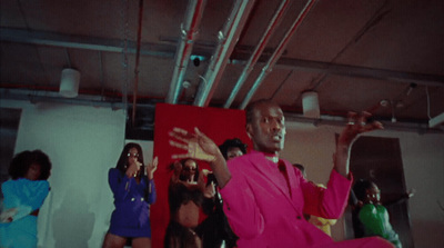 a man in a pink suit standing in front of a group of women