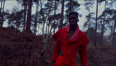 a man in a red outfit standing in the woods