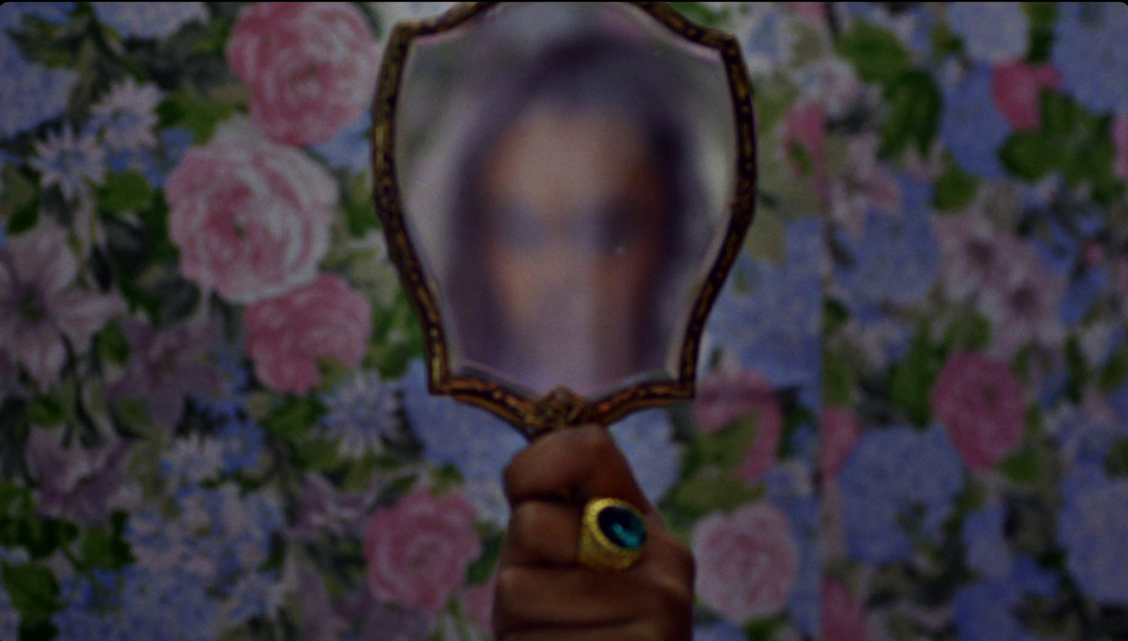 a hand holding a mirror with a woman's face in it