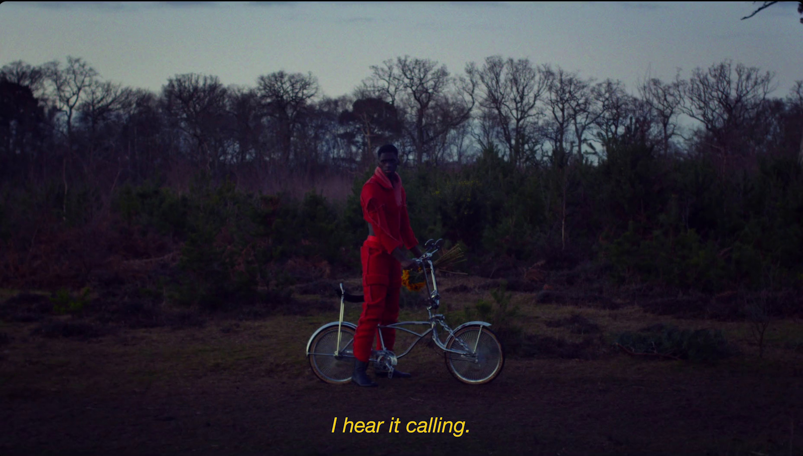 a man in a red jumpsuit standing next to a bicycle