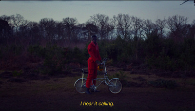 a man in a red jumpsuit standing next to a bicycle