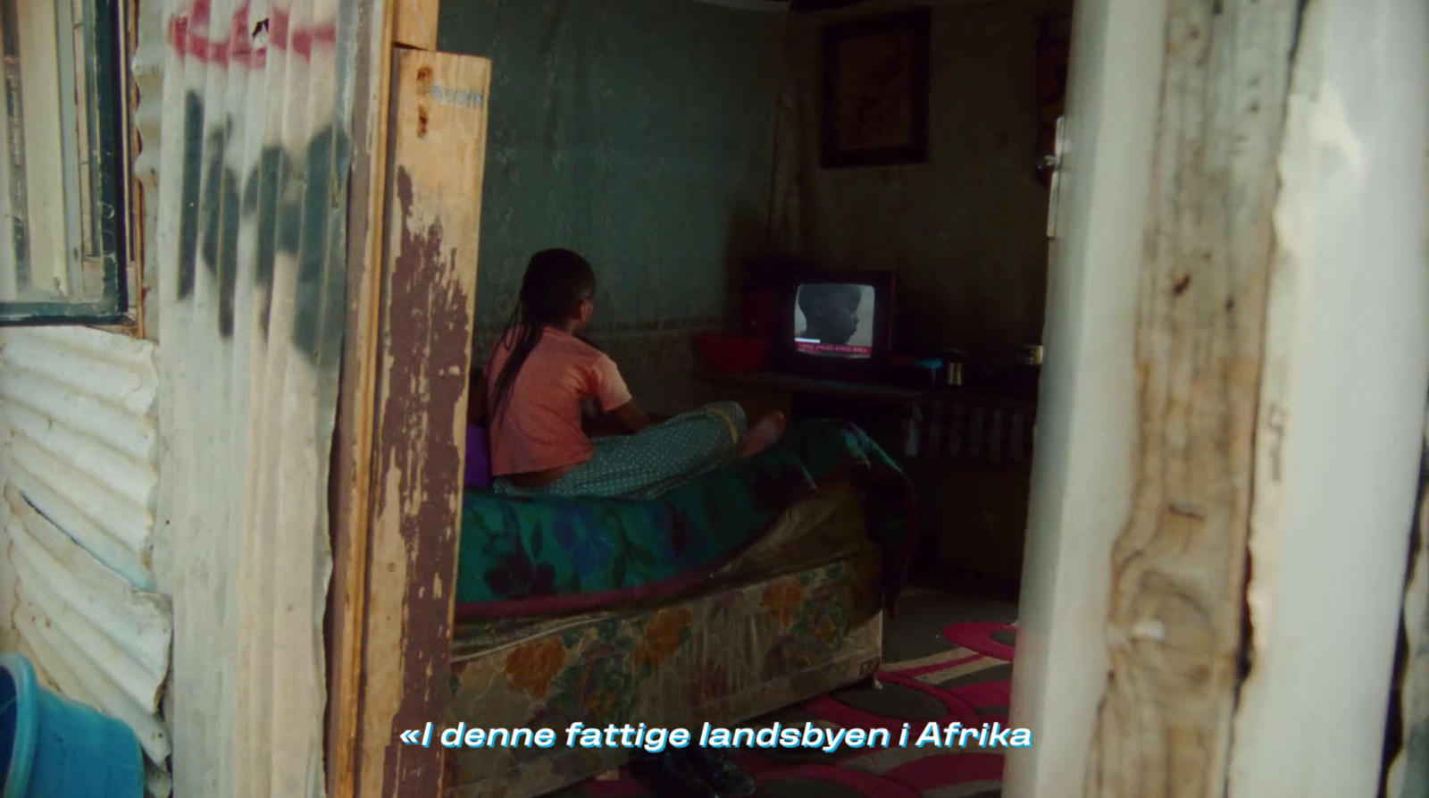 a woman sitting on a bed in a small room