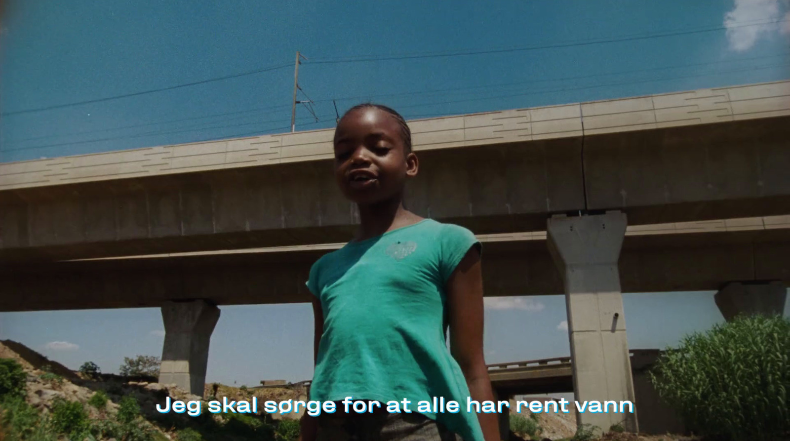 a young girl standing in front of a bridge