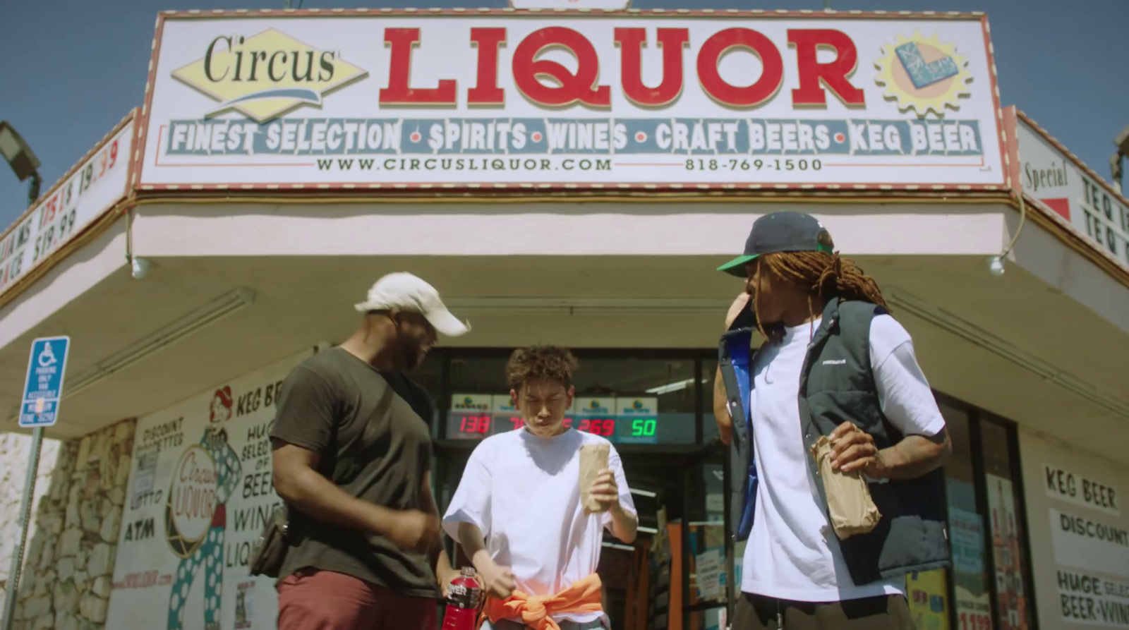 three men standing outside of a liquor store