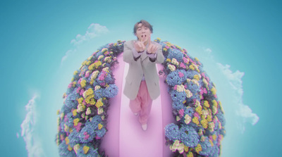 a man standing on top of a pink object surrounded by flowers