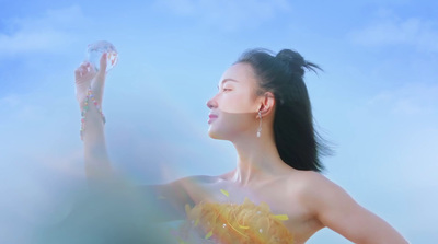 a woman in a yellow dress blowing bubbles