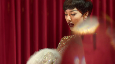 a woman in a red dress standing in front of a red curtain