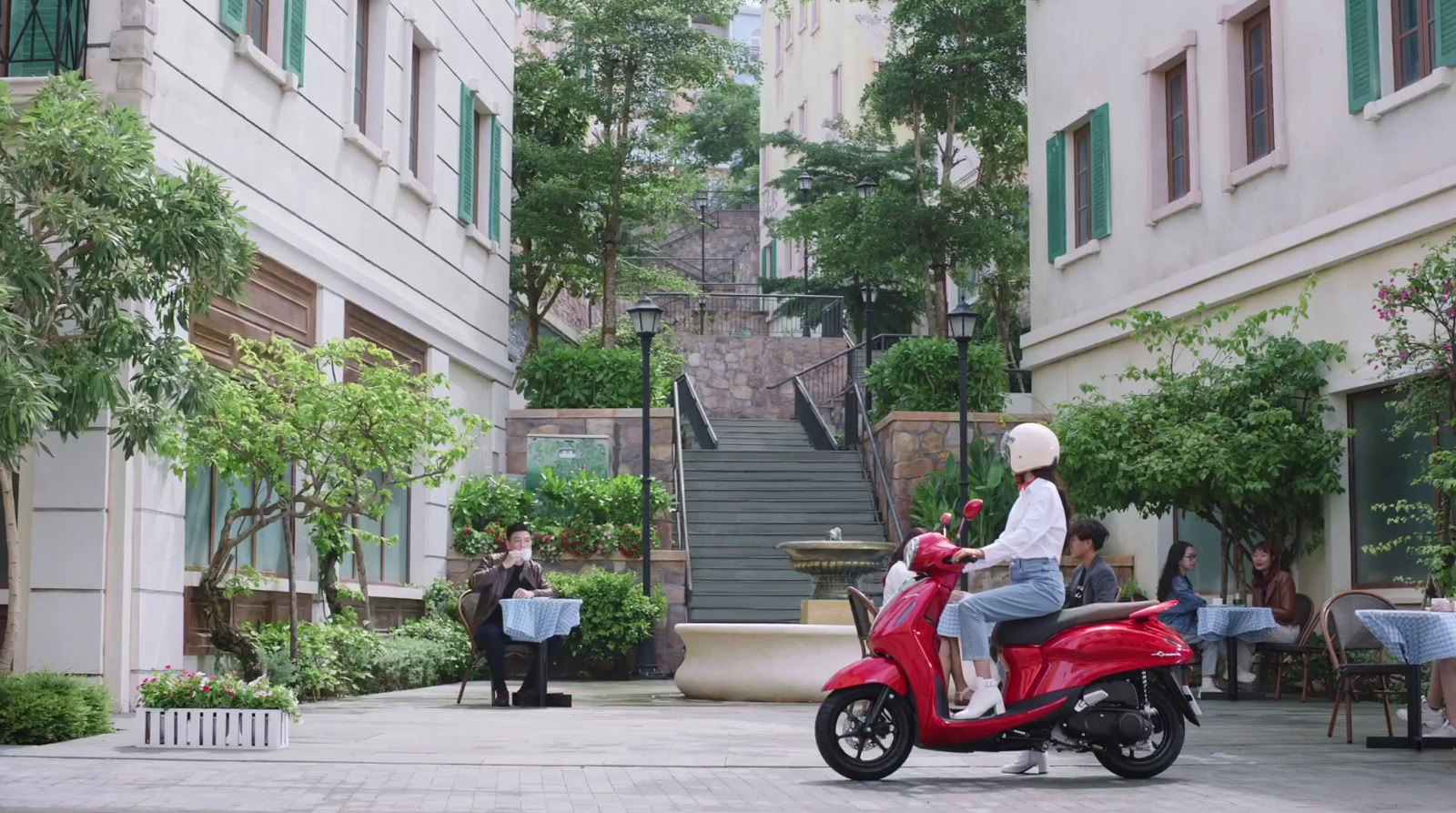 a woman riding a red scooter down a street