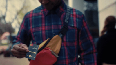 a man in plaid shirt holding a red and yellow purse