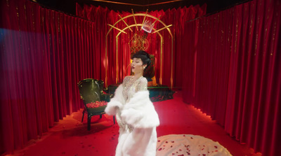 a woman in a white dress standing in front of a red curtain