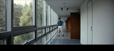 a man walking down a hallway next to a window