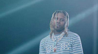 a man with dreadlocks standing in front of a blue background