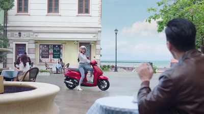 a man sitting on a red scooter taking a picture