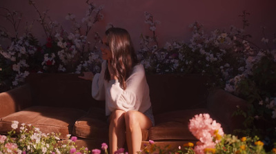 a woman sitting on a couch in front of flowers