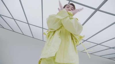 a woman in a yellow outfit standing under a metal structure