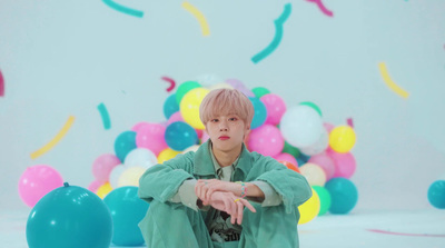 a boy sitting on the floor in front of balloons and confetti