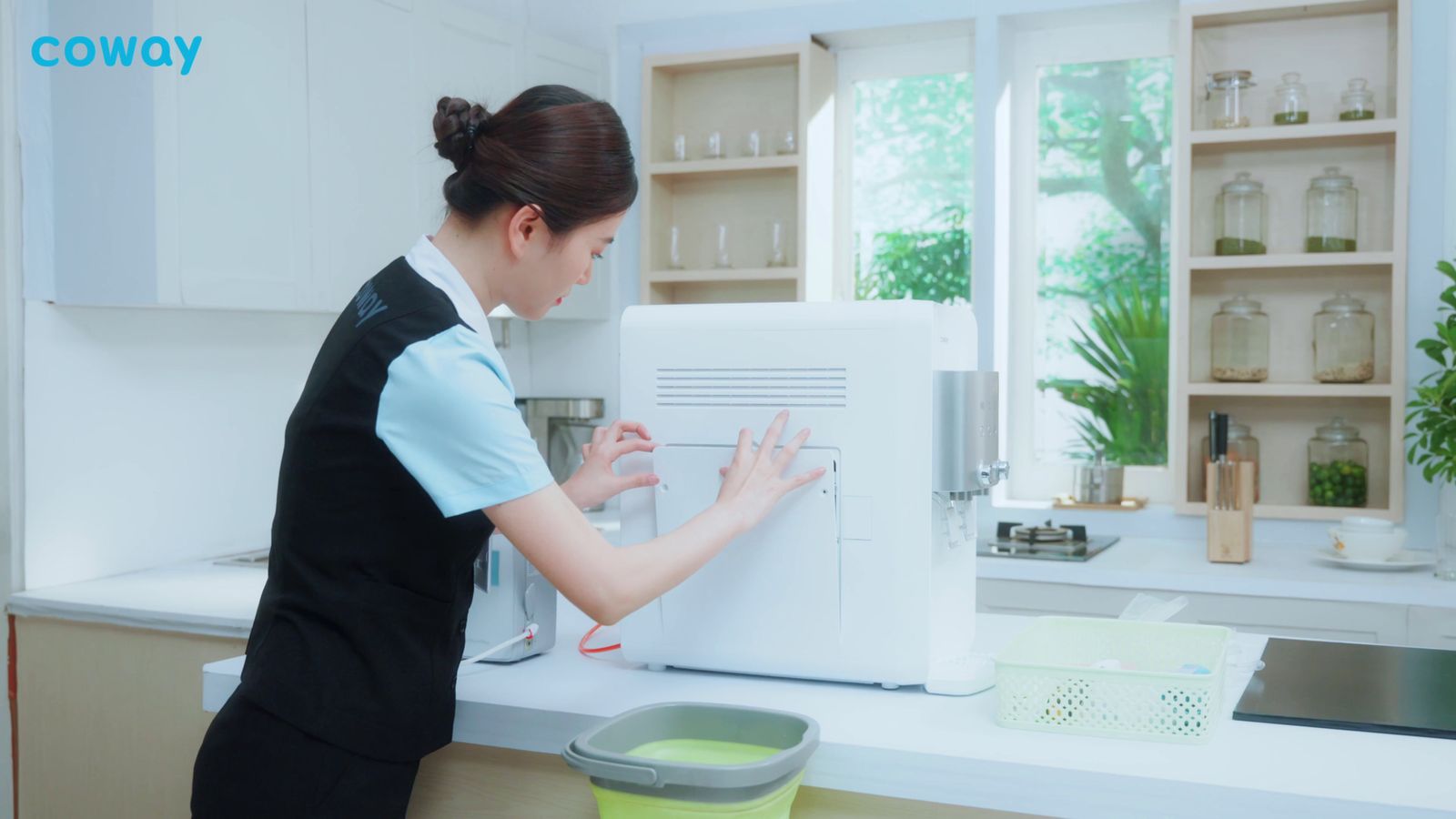 a woman in a black apron is using a microwave