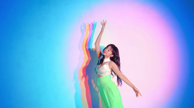 a woman standing in front of a rainbow colored wall