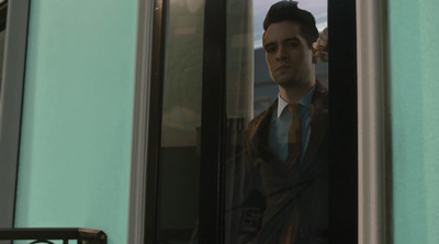 a man in a suit and tie looking out of a window