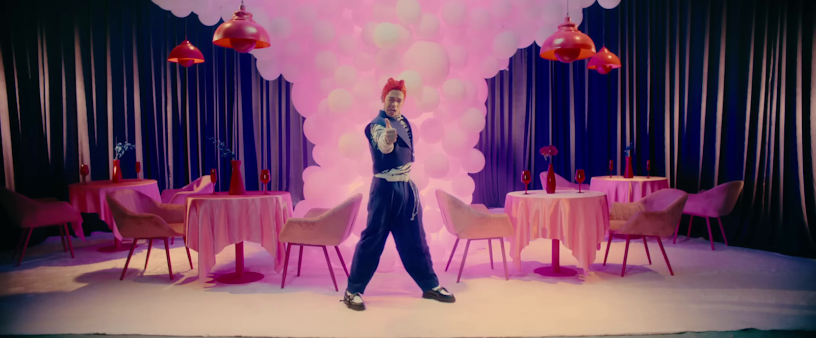 a man standing in front of a table with pink chairs