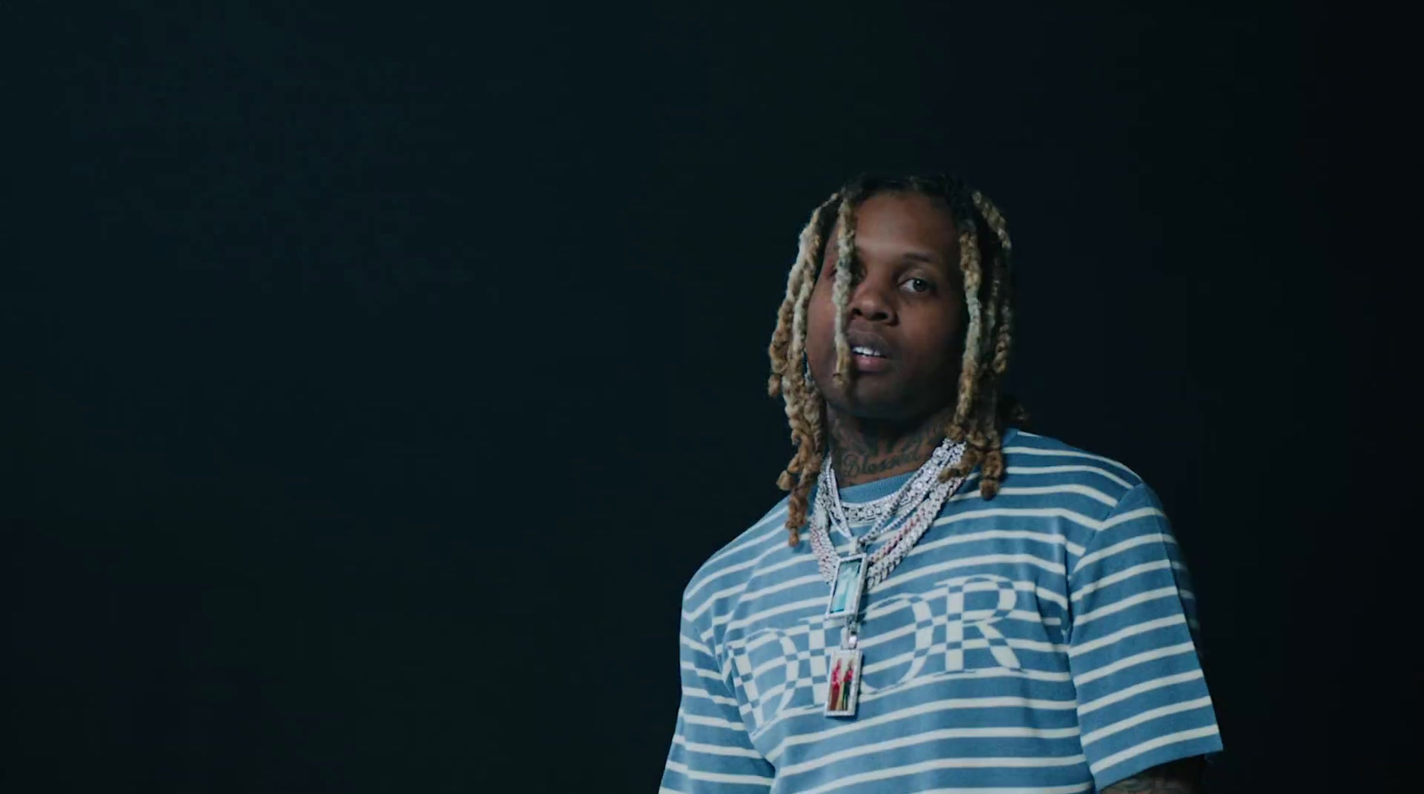 a man with dreadlocks standing in front of a black background