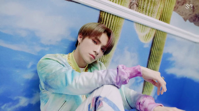 a young man sitting in front of a painting of a cactus