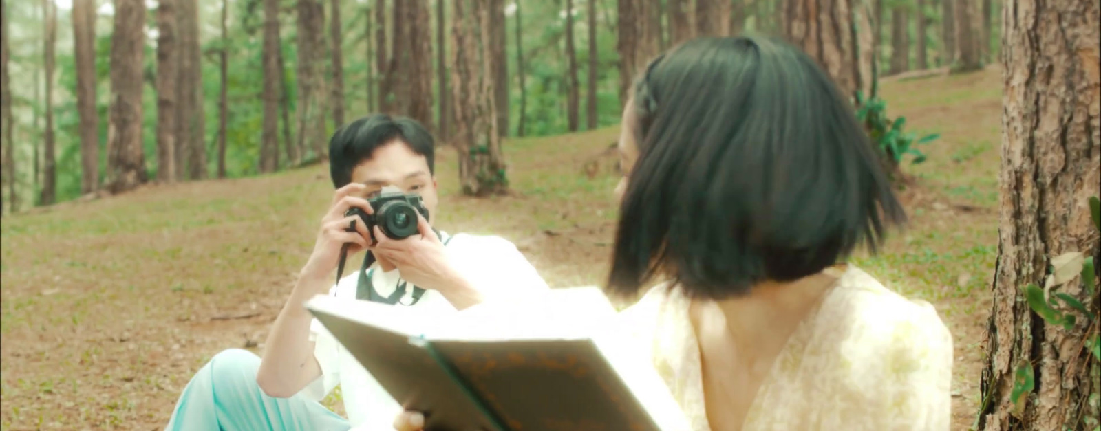 a woman taking a picture of a man in the woods