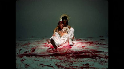 a man and woman sitting on the ground covered in blood