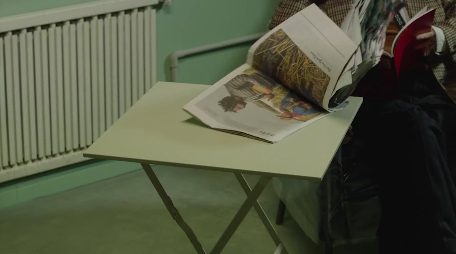 a person sitting at a table reading a newspaper