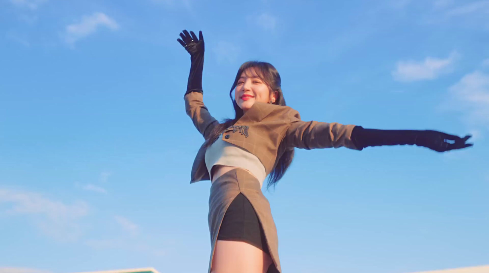 a woman in a short skirt and jacket is flying a kite