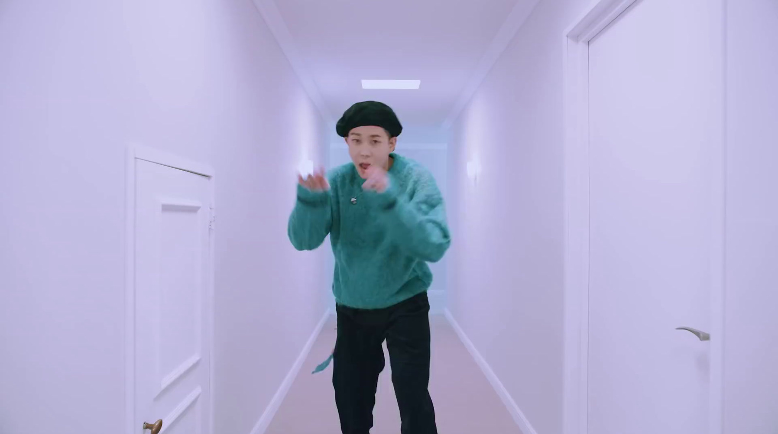 a man in a green sweater is standing in a hallway