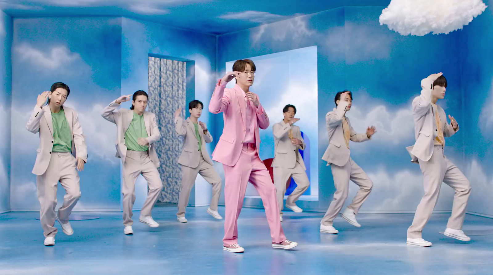 a man in a pink suit is dancing in front of a group of other men