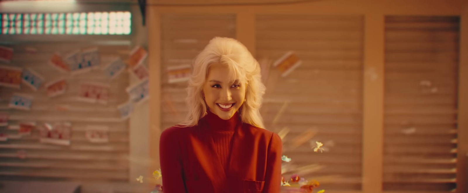 a woman in a red sweater standing in front of a christmas tree