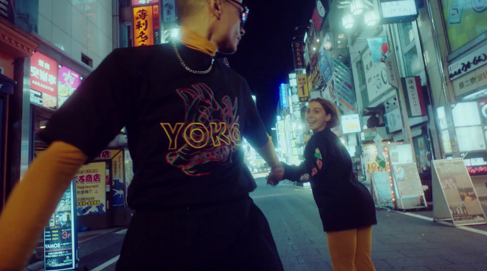 a man and woman walking down a street holding hands