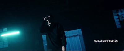 a man in a black hoodie standing in the dark