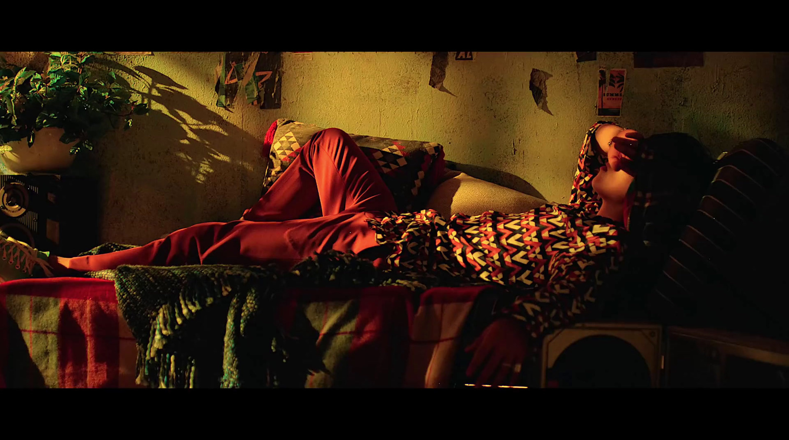 a woman laying on top of a couch next to a potted plant