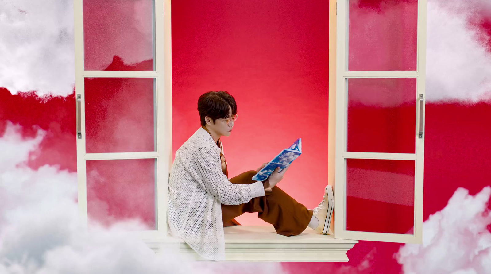 a person sitting on a window sill reading a book