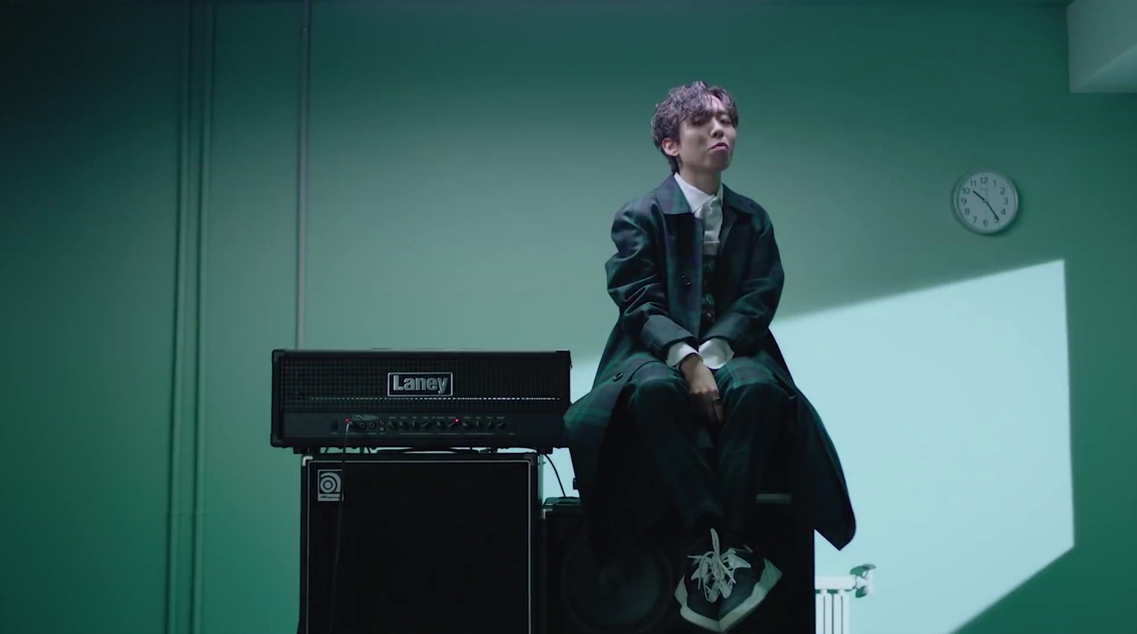 a man sitting on top of a amp in a room