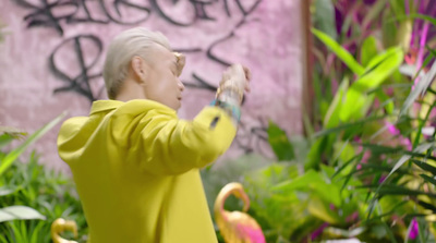 a woman in a yellow jacket taking a picture of some flamingos